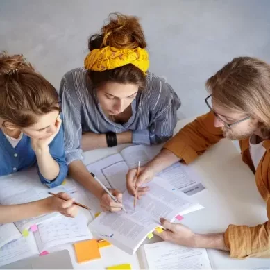 Drei Studenten besprechen die Inhalte Ihres Deutschkurses und üben das Leseverstehen.